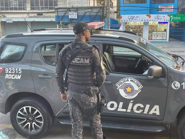 Foto colorida mostra policial militar da Rocam parado em frente a viatura