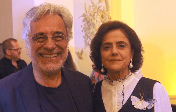 Aderbal Freire Filho e Marieta Severo. Ele está sorrindo, de óculos de grau, blazer e blusa azul escurto. Ela está de colete preto e blusa branca - Metrópoles