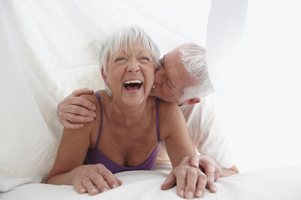 Foto de dois idosos sorrindo embaixo de cobertor - Metrópoles