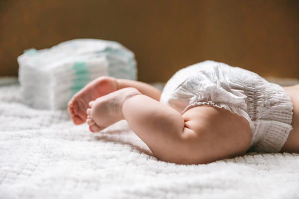 Imagem colorida mostra as pernas de um bebê de pele branca com uma fralda - Metrópoles