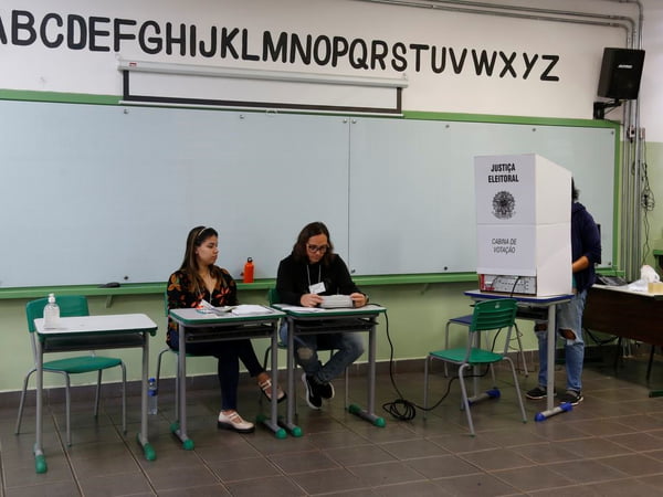 foto colorida de eleição do Conselho Tutelar em SP; detalhe com imagem da urna e mesários - Metrópoles