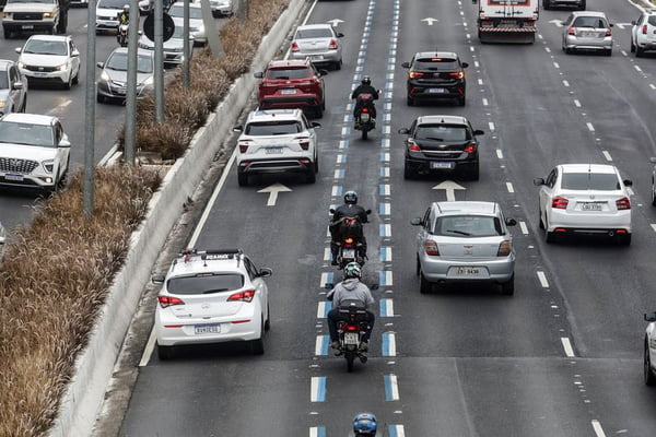 Imagem colorida mostra motos dentro da chamada faixa azul circulando com carros nas demais faixas da via em São Paulo - Metrópoles