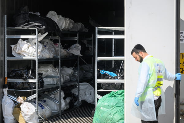 Equipe forense observa enquanto um contêiner refrigerado contendo os corpos de cidadãos israelenses mortos durante os recentes ataques do Hamas é aberto, durante uma visita às instalações que identificam o falecido em 13 de outubro de 2023 em Ramla