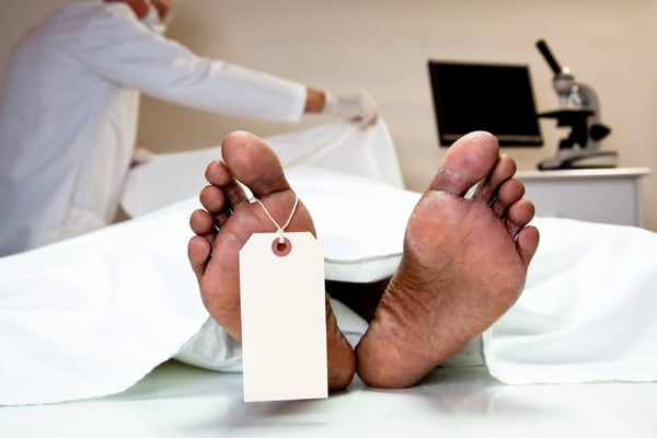 Foto mostra profissional da saúde cobrindo corpo de um paciente no necrotério