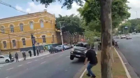 Imagem colorida mostra viatura da Rota com apenas duas rodas, as do lado esquerdo do veículo, no asfalto, durante manobra que derrubou um poste e acertou uma moto no centro de São Paulo - Metrópoles