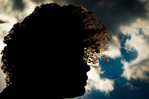 Imagem colorida mostra sombra de pessoa de cabelos crespos, com céu ao fundo - Metrópoles
