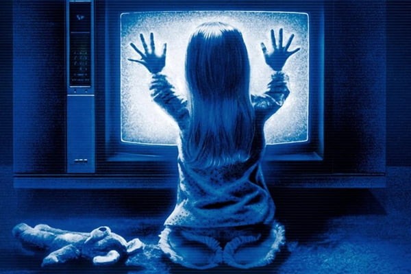 Imagem do filme Poltergeist. Uma criança na frente de uma televisão em filtro azul - Metrópoles