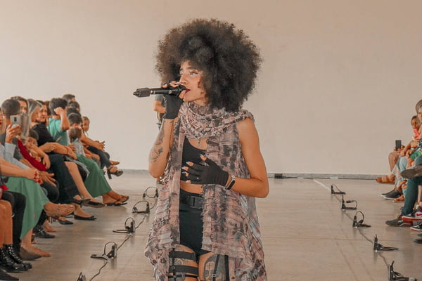 Na imagem com cor, mulher negra canta durante apresentação - Metrópoles