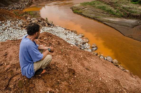 Imagem colorida de homem vendo lama de barragem em MG - Metrópoles
