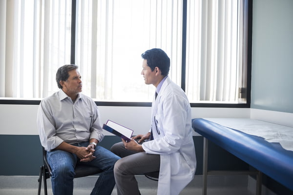 Foto mostra homem em consulta médica com um médico em um consultório amplo - Metrópoles - machismo