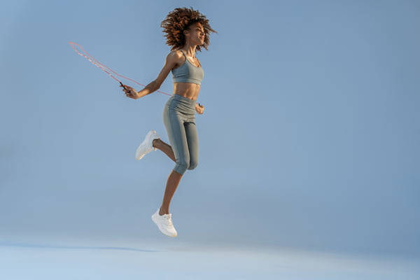 Vista lateral da mulher pulando corda no fundo do estúdio. Melhor treino cardiovascular - Metropoles