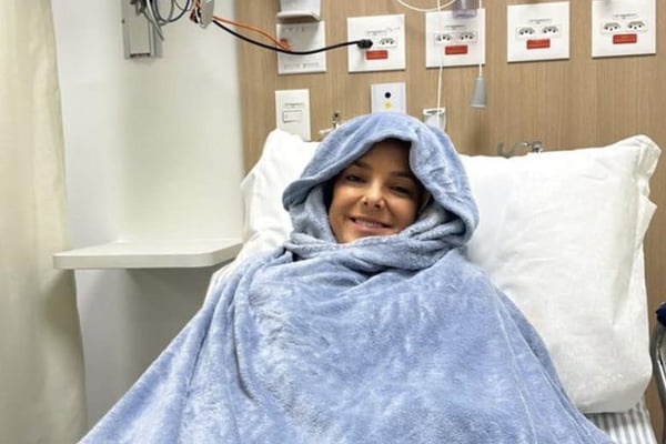 Foto de uma mulher embrulhada em um edredom em uma cama de hospital - Metrópoles