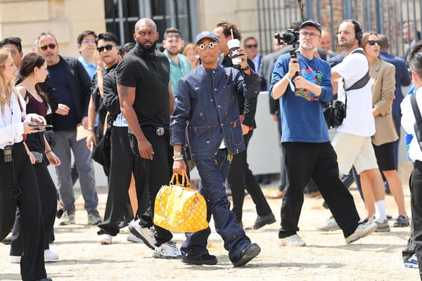 Na imagem com cor, Pharrell Williams andando durante o Paris Fashion Week com bolsa feita de pele de crocodilo - Metrópoles