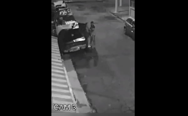 Imagem preto e branco mostra mulher tentando fugir de tentativa de estupro em São Paulo. Na cena, ela está ao lado de um homem com boné e de carro coberto por uma lona - metrópoles