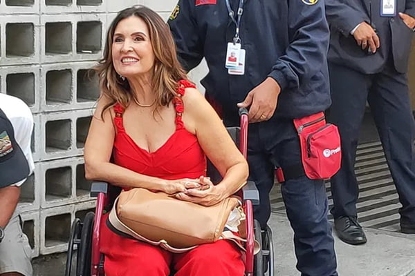 Foto de Fátima Bernardes em uma cadeira de rodas. Ela usa look vermelho - Metrópoles