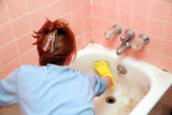 mulher limpando uma banheira com mofo