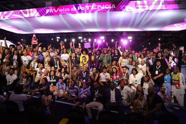 imagem colorida mostra grupo grande de pessoas posando para foto em palco da expo favela - metrópoles