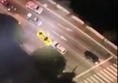 Imagem aérea de veículos em avenida; uma viatura da PM cerca um Camaro amarelo - Metrópoles