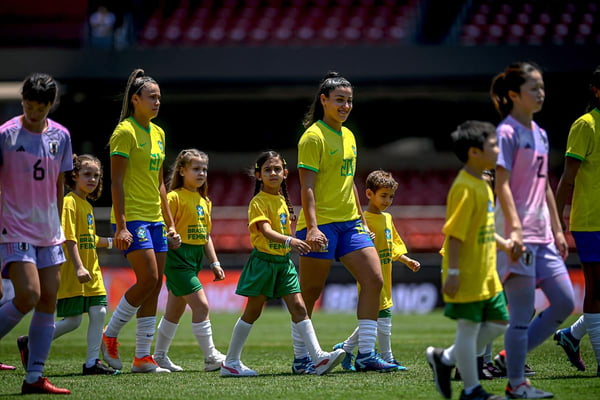 Imagem colorida das jogadoras do Brasil ao lado de torcedores - Metrópoles