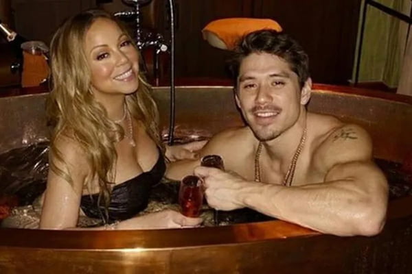 Mariah Carey e Bryan Tanaka em foto colorida. Eles estão em um ofurô, sorrindo - Metrópoles