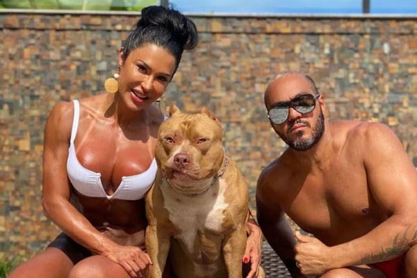 Foto colorida de um casal com um cachorro - Metrópoles