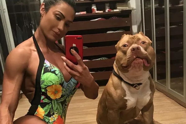 Foto colorida de um casal com um cachorro - Metrópoles