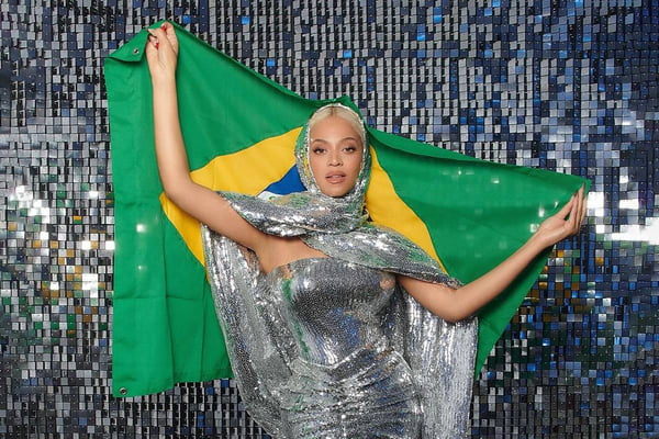 Foto de mulher com roupa de paetês. Ela segura a bandeira do Brasil - Metrópoles