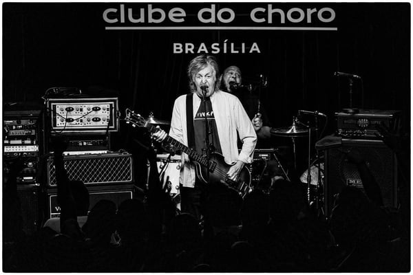 Paul McCartney se apresenta no Clube do Choro, em Brasília. Foto em preto e branco mostra cantor tocando e cantando - Metrópoles