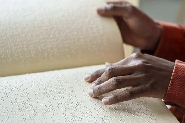 Fotografia mostra mãos de mulher lendo livro em braille - Metrópoles