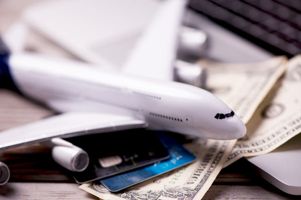 Imagem de miniatura de avião sobre cédulas de dinheiro e cartões de crédito - Metrópoles