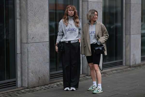 Na rua, duas mulheres usam looks combinando com moletom cinza e tênis esportivo - Metrópoles