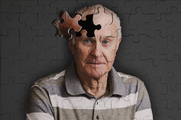 Foto de quebra-cabeça com a foto de um idoso. Falta uma peça bem na parte da cabeça do cabeça