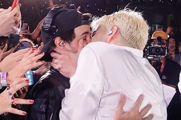Foto colorida de Jão beijando seu produtor - Metrópoles