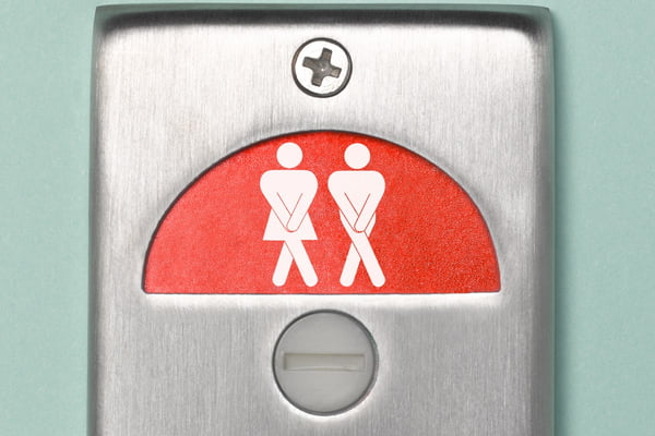 Imagem mostra uma trava de banheiro público com o sinal de duas pessoas com as pernas e braços cruzados - Metrópoles