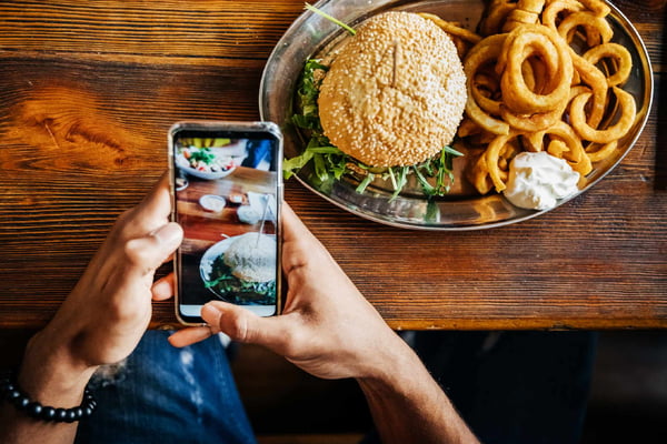 Pessoa tira foto de hambúguer, fast food, comida redes sociais - Metrópoles