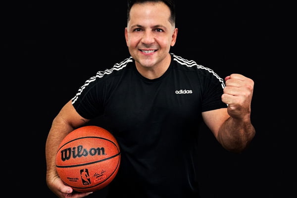 Marco Marconi posa de blusa preta e com uma bola de basquete na mão - Metrópoles