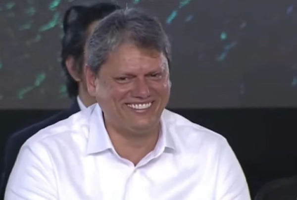 Foto colorida do governador Tarcísio de Freitas sorrindo em evento com Lula em Santos - MEtrópoles