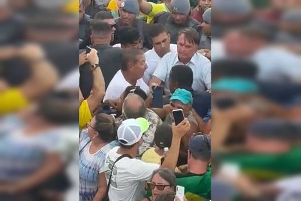 Fotografia colorida de multidão ao redor do ex-presidente Jair Bolsonaro