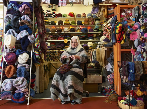Na imagem com cor, mulher branca posa em frente à loja de crochê e tricô - Metrópoles