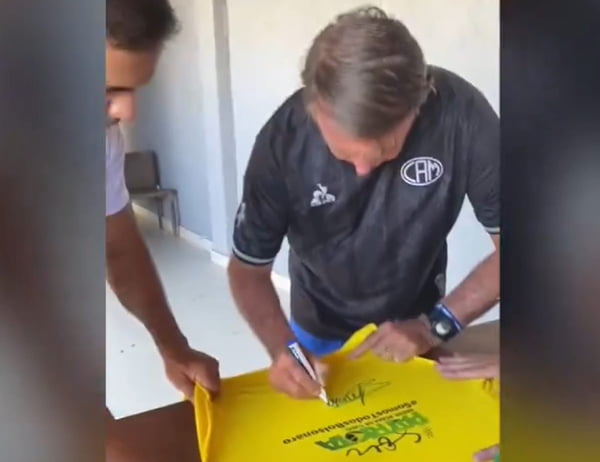 Imagem colorida do ex-presidente Jair Bolsonaro (PL) autografando camisa de um apoiador - Metrópoles