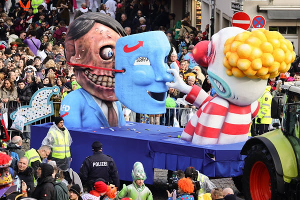 Carro alegórico na Alemanha mostra uma efígie de Adolf Hitler sendo desmascarada enquanto um carnavalesco retira sua máscara do partido de extrema direita AfD
