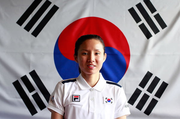 Foto colorida de Nam Hyun- Hee em frente à bandeira sul-coreana - Metrópoles