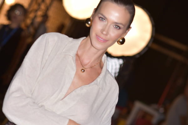 Renata Kuerten posa com uma blusa branca e cabelos presos - Metrópoles