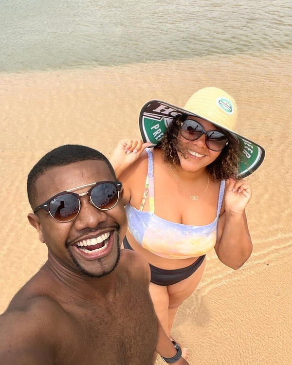 Davi e a esposa, Mani Rêgo posam juntos e sorridentes na praia - Metrópoles