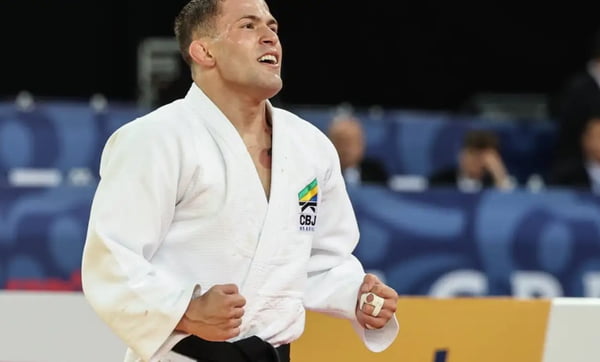 Foto colorida mostra o judoca Willian Lima com um kimono branco comemorando vitória
