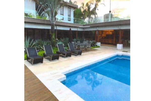 Imagem colorida mostra área externa de casa de luxo com piscina