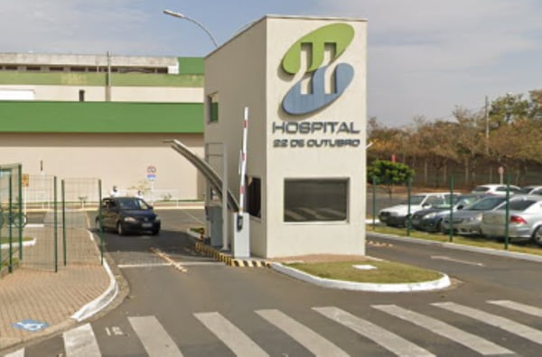 Imagem colorida da fachada do Hospital 22 de Outubro, na imagem também aparecem carros. Metrópoles