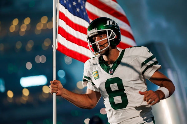 Aaron Rodgers #8 do New York Jets corre em campo com a badeira dos Estados Unidos antes de jogo da NFL contra Buffalo Bills em 11 de setembro de 2023