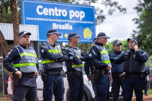 Foto tirada de dia de policias da PMDF em frente a placa azul com os dizeres: Centro Pop Brasília