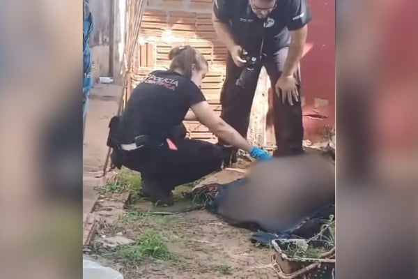 Imagem colorida mostra agentes da polícia perto de corpo de pit-bull morto com golpes de garfo de churrasco - Metrópoles